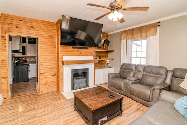 living room with wooden walls, ceiling fan, and light wood-type flooring