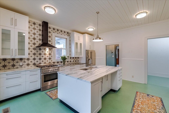 kitchen with white cabinetry, wall chimney range hood, premium appliances, backsplash, and a center island with sink