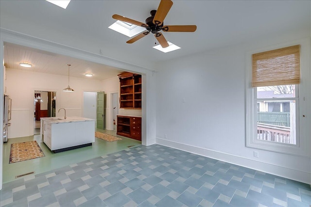 unfurnished living room featuring ceiling fan and sink