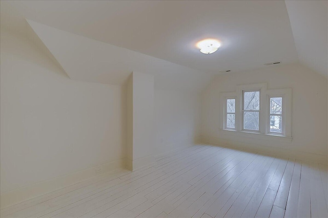 spare room with light hardwood / wood-style flooring and vaulted ceiling