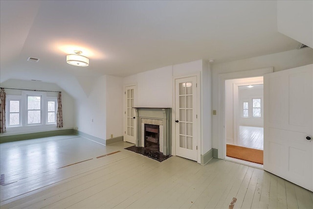 unfurnished living room featuring light hardwood / wood-style floors and a tiled fireplace