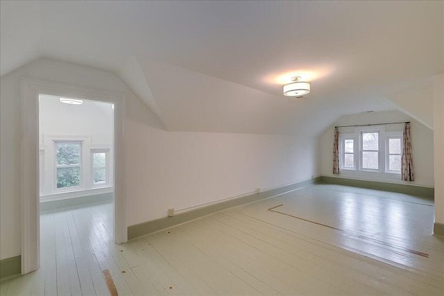 additional living space featuring lofted ceiling and light wood-type flooring