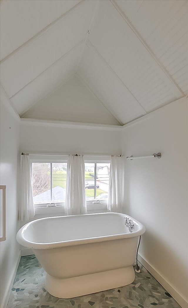 bathroom featuring lofted ceiling and a tub to relax in