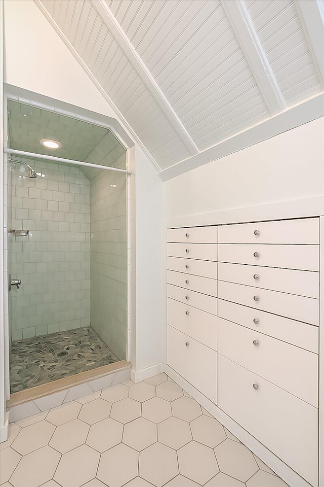 bathroom featuring a tile shower, tile patterned floors, and vaulted ceiling