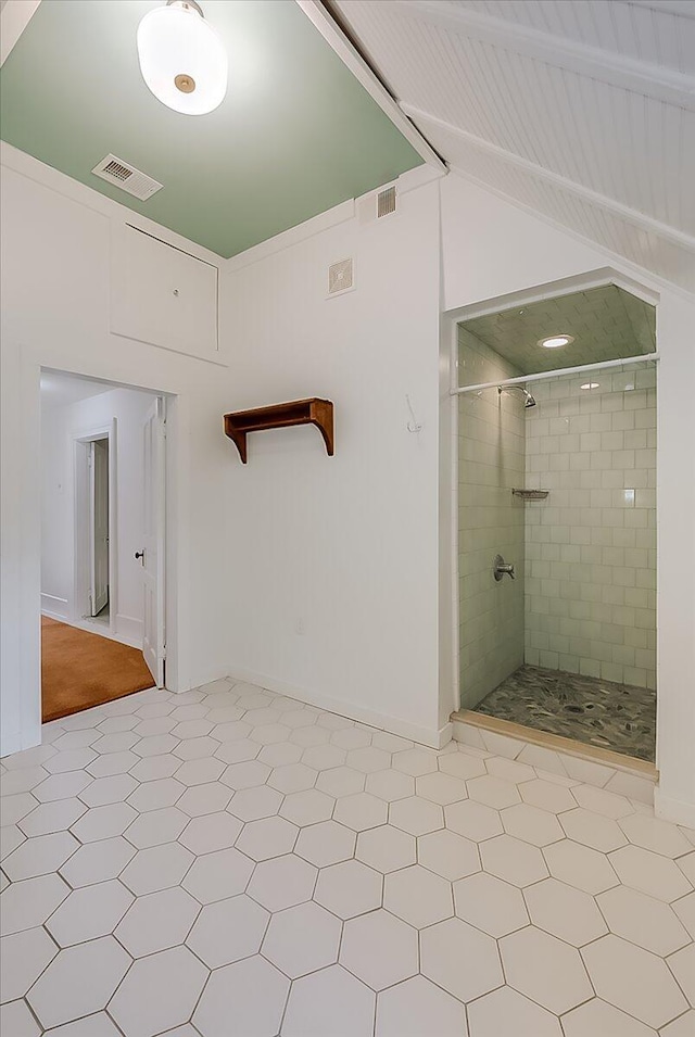 bathroom featuring a tile shower, vaulted ceiling, and tile patterned floors