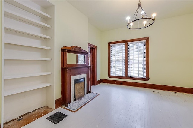 unfurnished living room with a chandelier and light hardwood / wood-style floors