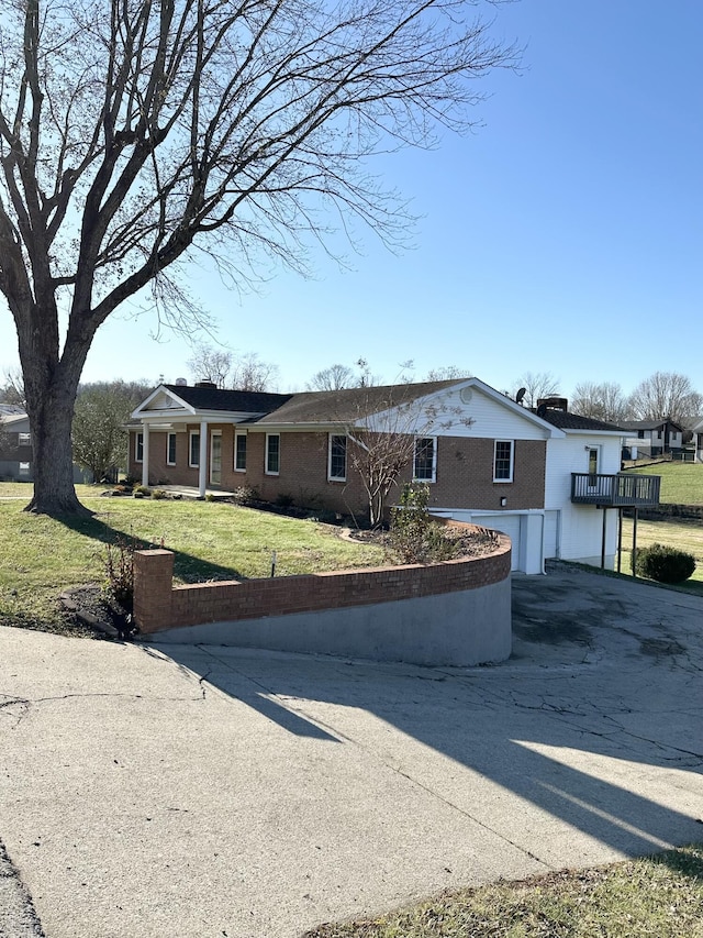 view of front of house with concrete driveway, brick siding, and a front lawn