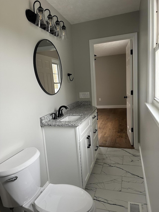 bathroom with visible vents, toilet, marble finish floor, baseboards, and vanity