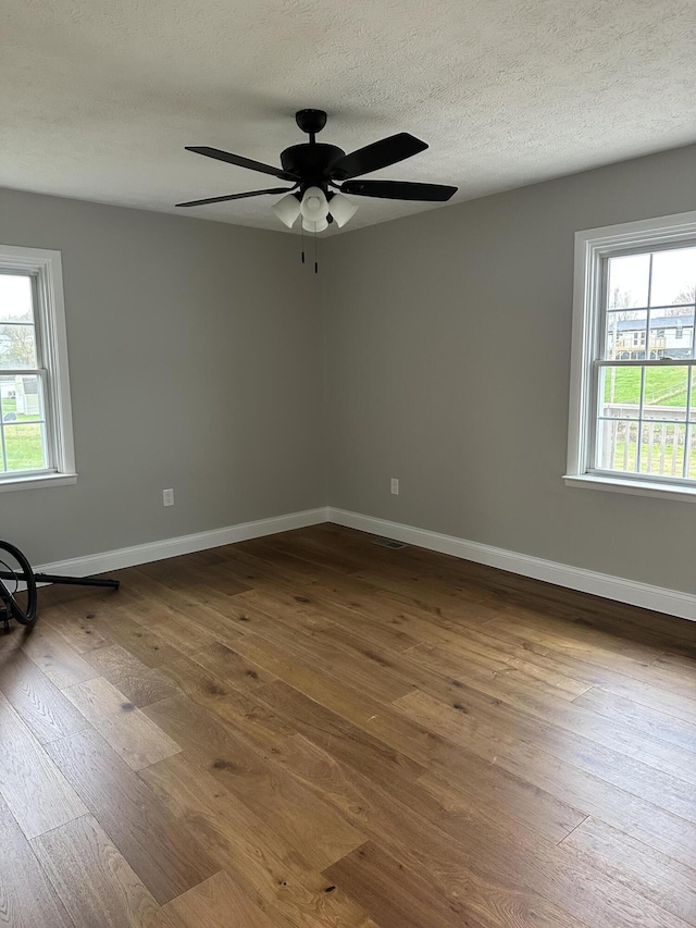 spare room featuring dark wood finished floors, a ceiling fan, baseboards, and a textured ceiling