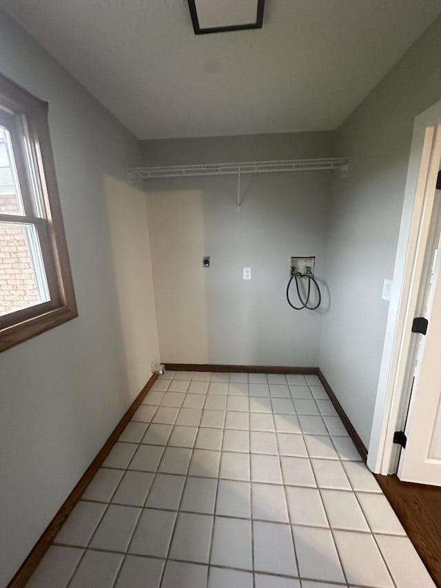 interior space with light tile patterned floors, baseboards, hookup for an electric dryer, and hookup for a washing machine