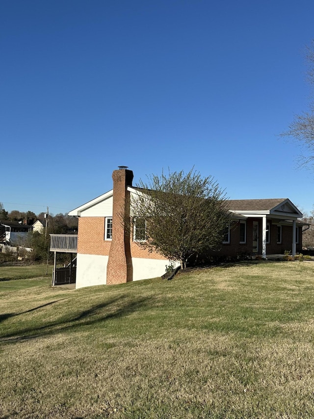 view of side of property with a lawn and a chimney