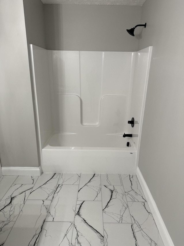 bathroom with baseboards, marble finish floor, and  shower combination