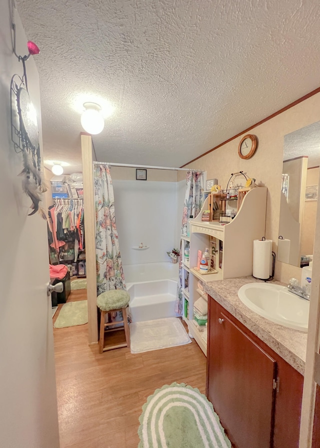 bathroom featuring hardwood / wood-style floors, shower / bathtub combination with curtain, and a textured ceiling