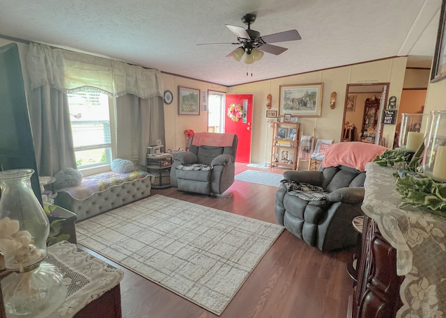 living room featuring lofted ceiling, dark wood-type flooring, crown molding, ceiling fan, and a textured ceiling