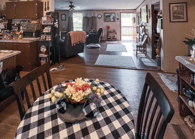 dining space with ceiling fan, a textured ceiling, a wealth of natural light, and dark wood-type flooring