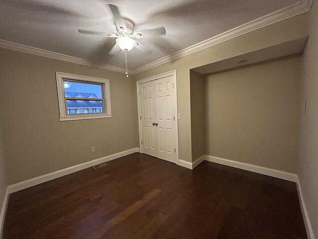 unfurnished bedroom with ceiling fan, dark wood-type flooring, a closet, and ornamental molding