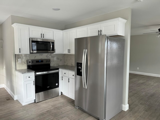 kitchen with hardwood / wood-style floors, light stone counters, white cabinetry, and stainless steel appliances