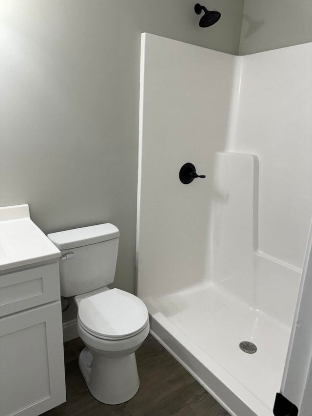 bathroom featuring a shower, wood-type flooring, vanity, and toilet