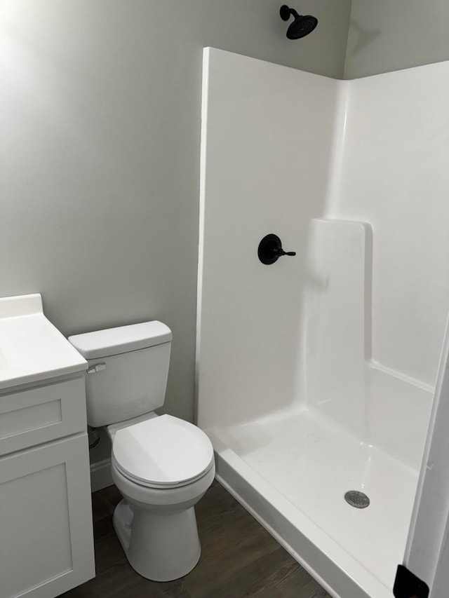 bathroom with hardwood / wood-style floors, toilet, a shower, and vanity