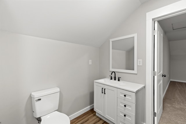 bathroom with hardwood / wood-style flooring, vanity, lofted ceiling, and toilet