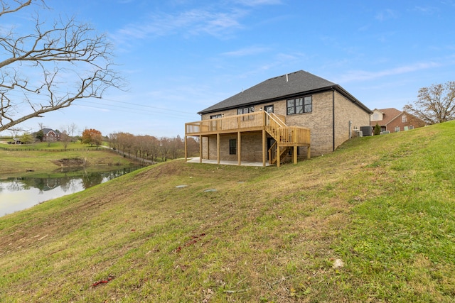 back of house with a deck with water view, a yard, and central AC