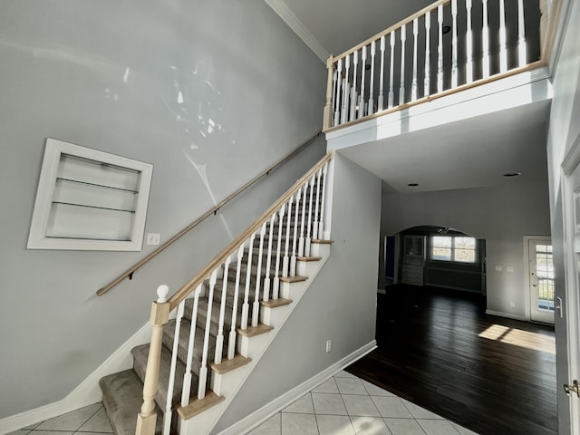 staircase featuring wood-type flooring, high vaulted ceiling, and ornamental molding