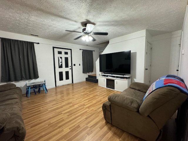 living room with a textured ceiling, light hardwood / wood-style floors, and ceiling fan