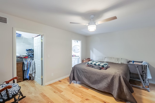 bedroom with ceiling fan, a walk in closet, light wood-type flooring, and a closet