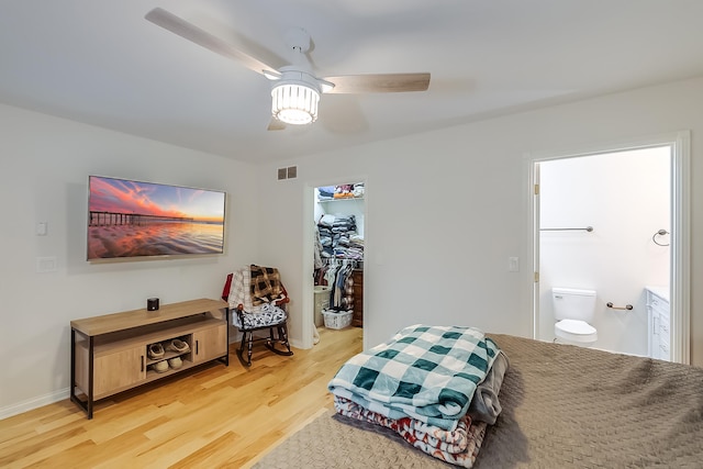 bedroom featuring a walk in closet, hardwood / wood-style flooring, ceiling fan, connected bathroom, and a closet