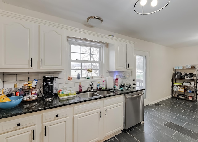 kitchen featuring decorative backsplash, white cabinets, sink, dark stone countertops, and dishwasher