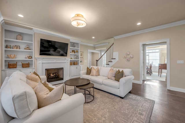 living room with crown molding, built in features, and hardwood / wood-style flooring