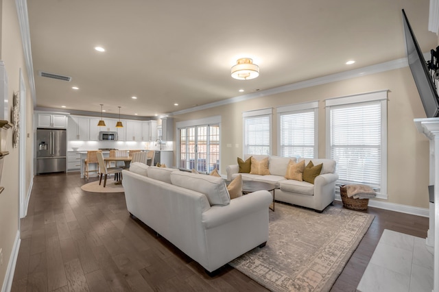 living room with dark hardwood / wood-style floors, ornamental molding, and a tiled fireplace