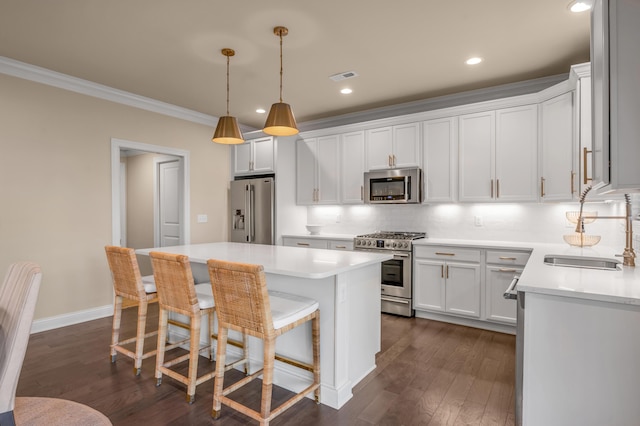 kitchen featuring stainless steel appliances, crown molding, sink, white cabinets, and a center island