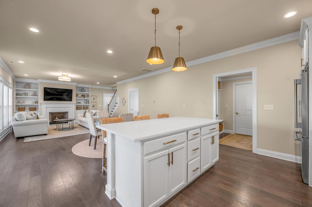 kitchen with a kitchen bar, crown molding, decorative light fixtures, white cabinets, and a center island