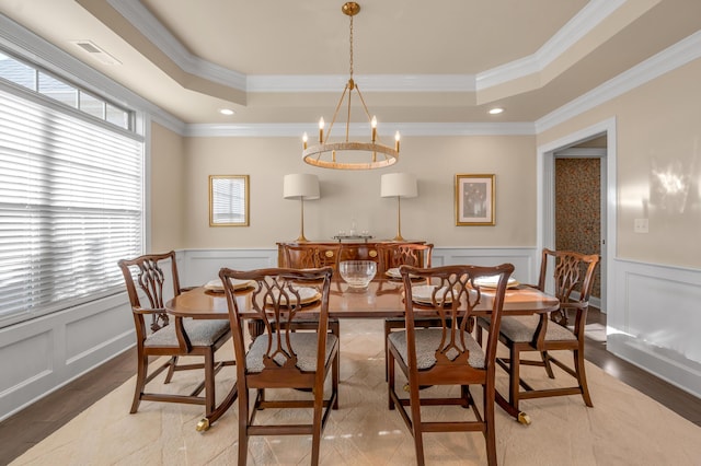 dining area featuring a raised ceiling, a chandelier, and ornamental molding