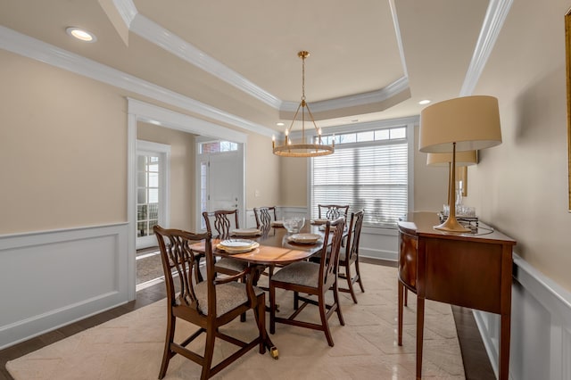 dining space featuring a raised ceiling, crown molding, hardwood / wood-style floors, and an inviting chandelier