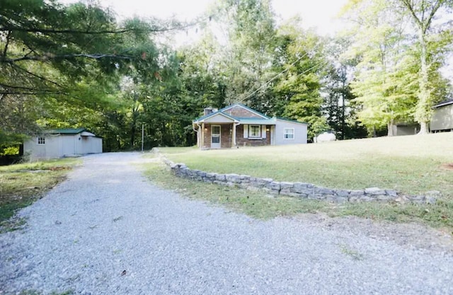 single story home featuring covered porch, an outbuilding, and a front lawn