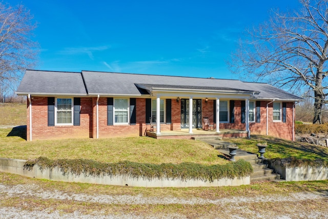 ranch-style home featuring covered porch, brick siding, and a front lawn