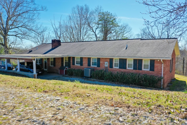 ranch-style house featuring brick siding, roof with shingles, a chimney, central AC unit, and an attached carport