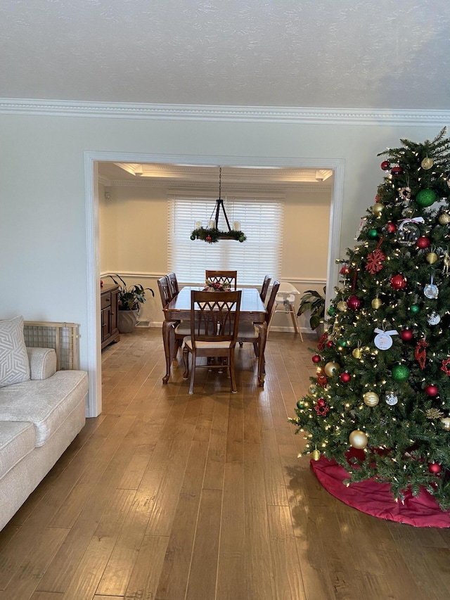 dining room with hardwood / wood-style floors, ornamental molding, and a textured ceiling