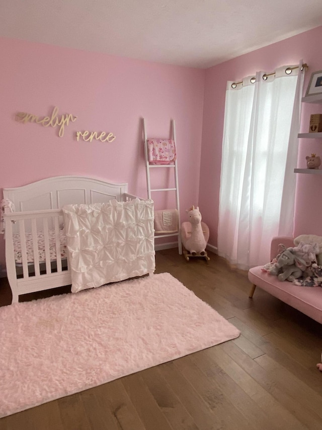 bedroom with a crib and wood-type flooring