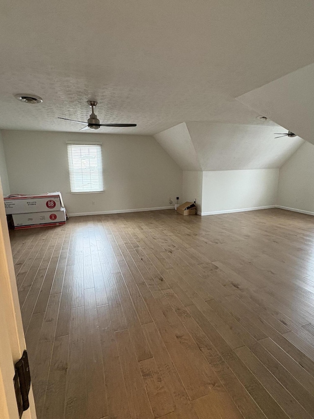 additional living space featuring lofted ceiling, wood-type flooring, and a textured ceiling