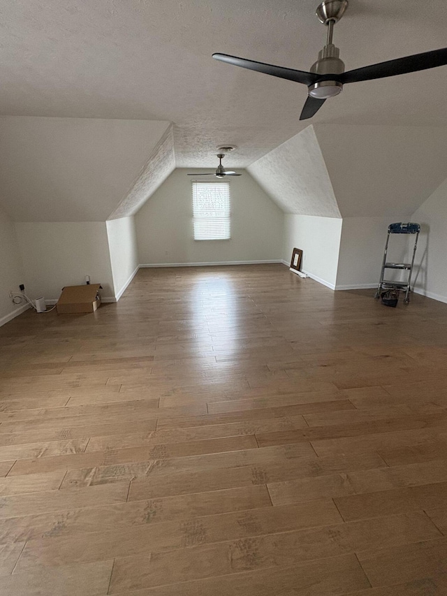 bonus room featuring ceiling fan, lofted ceiling, a textured ceiling, and light hardwood / wood-style flooring