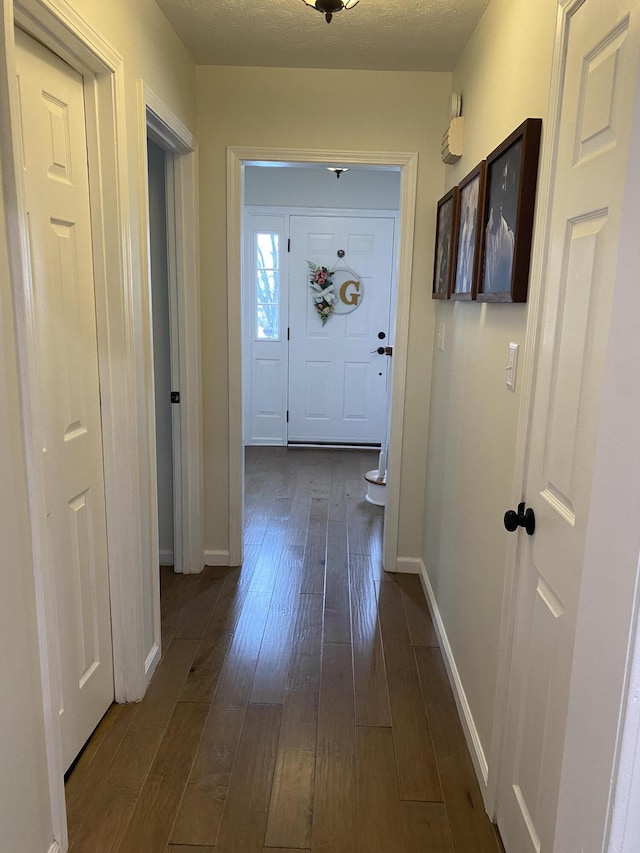 hall featuring a textured ceiling and dark hardwood / wood-style flooring