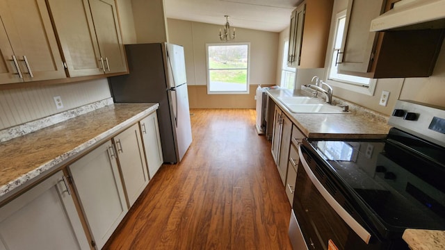 kitchen with light countertops, stainless steel appliances, under cabinet range hood, lofted ceiling, and a sink