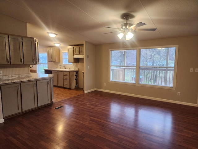kitchen with baseboards, visible vents, a ceiling fan, and dark wood finished floors