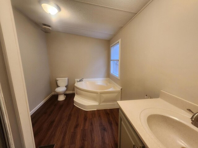 bathroom with wood finished floors, vanity, toilet, a textured ceiling, and a bath
