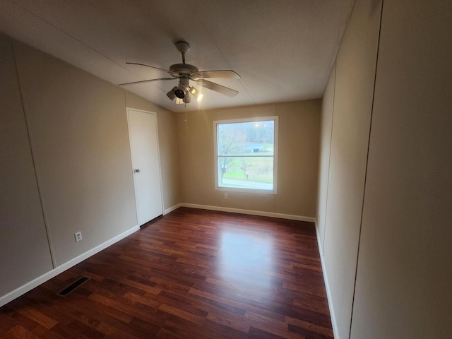 unfurnished room with baseboards, dark wood-style flooring, visible vents, and a ceiling fan