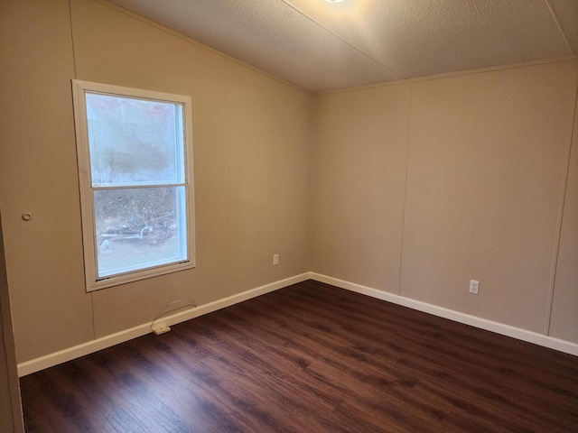 spare room with a textured ceiling, dark wood-style floors, baseboards, and vaulted ceiling