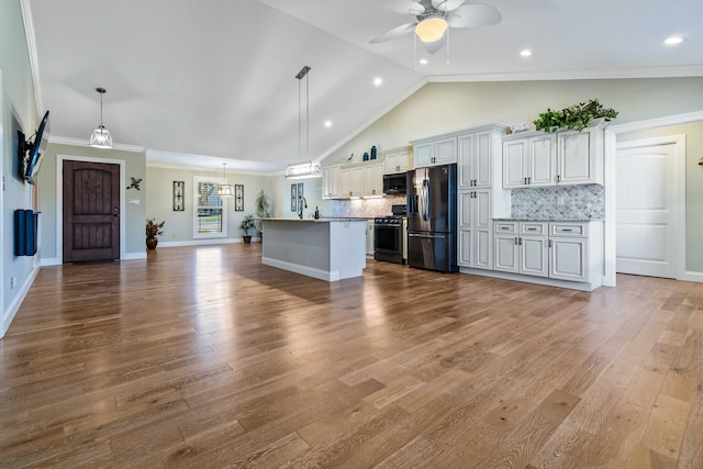 kitchen featuring appliances with stainless steel finishes, ornamental molding, decorative light fixtures, light hardwood / wood-style floors, and lofted ceiling